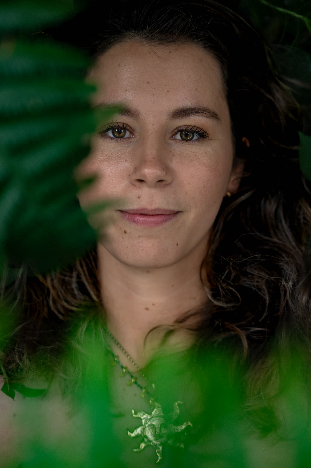 Close portrait of a woman framed by green leaves