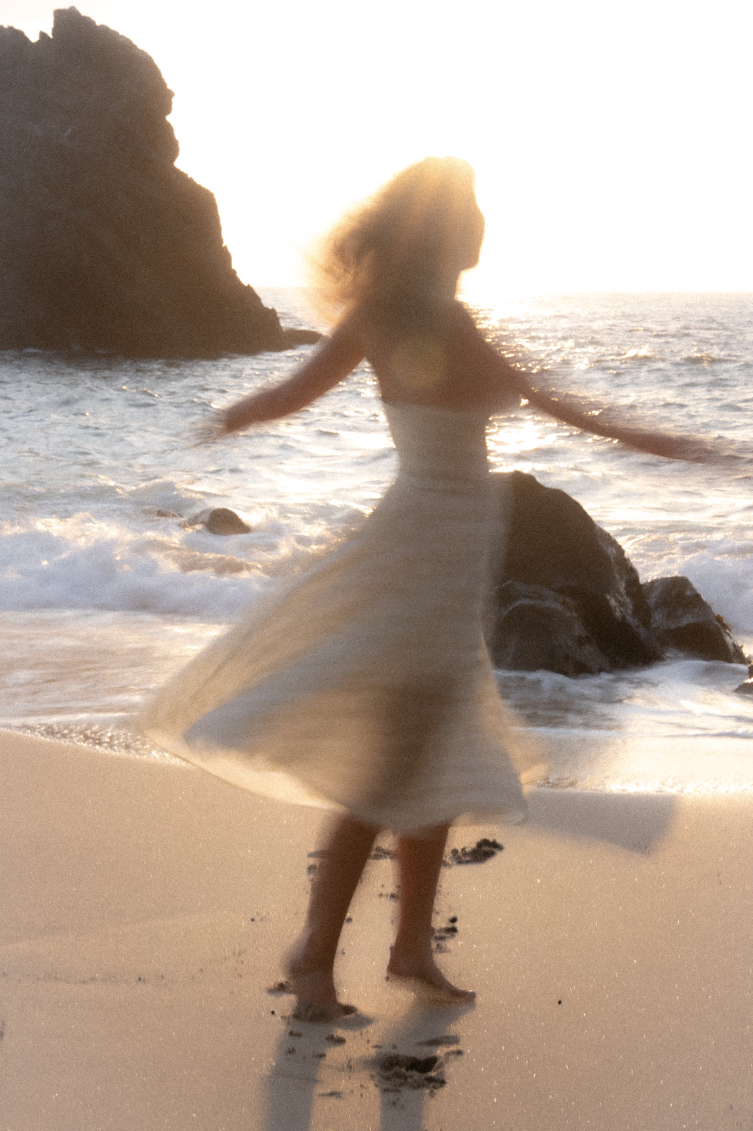 Woman twirling in a white dress in the surf