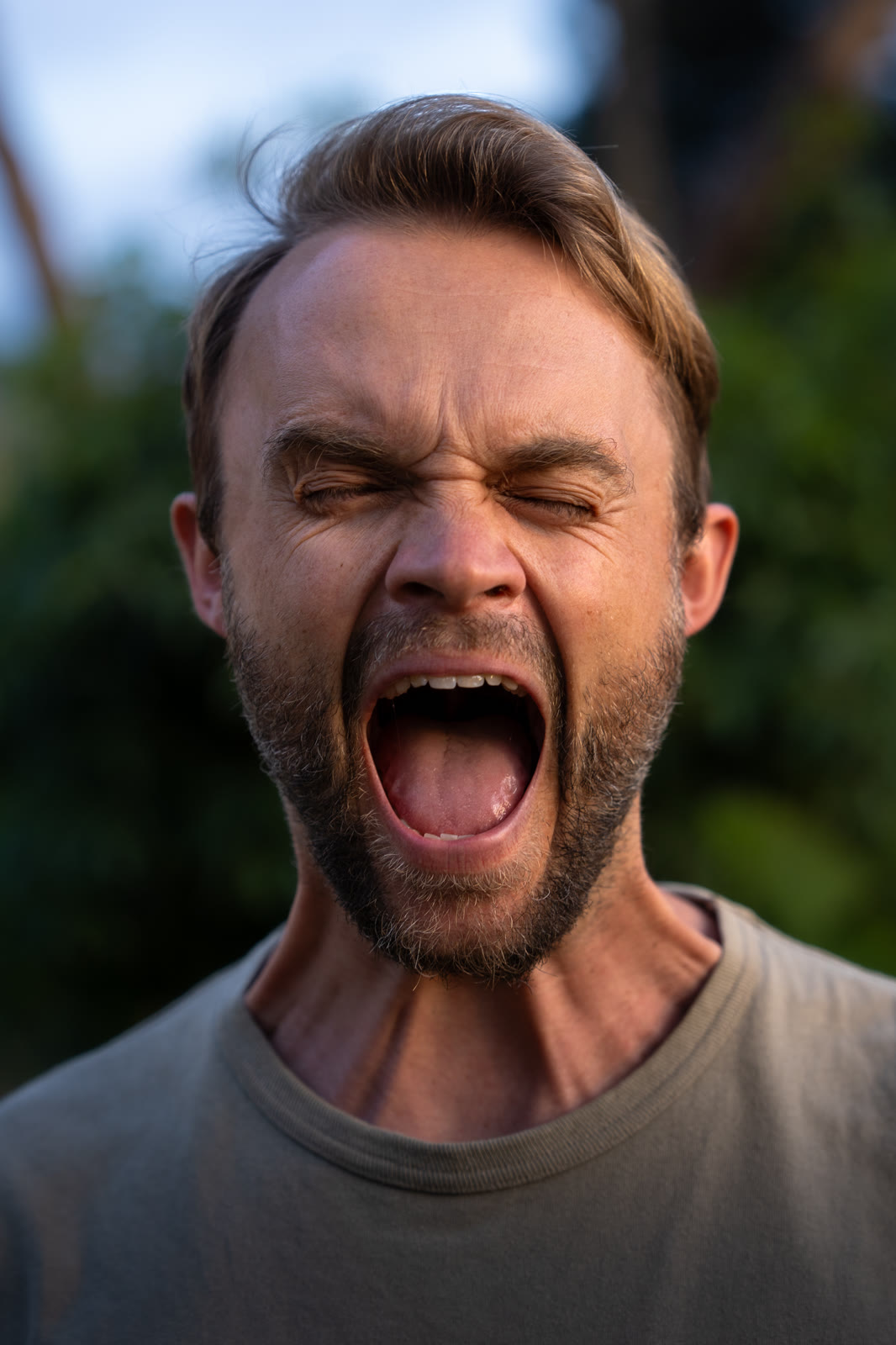 Man shouting with his eyes closed, outdoors